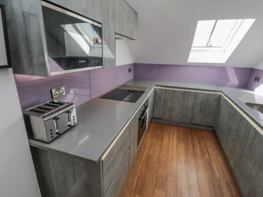A kitchen with grey cabinets a toaster an electric hob an oven and a skylight at Foxton Penthouse in Whitby