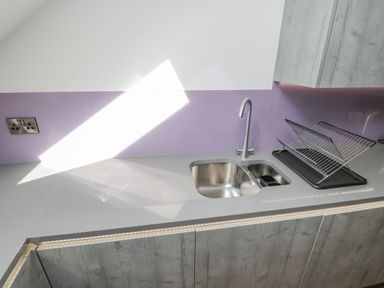 A kitchen countertop with a double stainless steel sink a drying rack and grey cabinets at Foxton Penthouse in Whitby