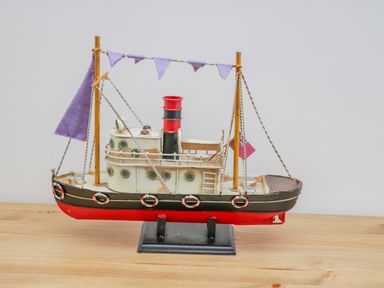 A model of a ship with purple flags on a wooden surface at Foxton Penthouse in Whitby