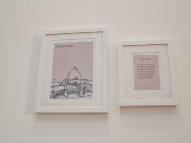 Two framed artworks on a white wall one with sketch of whale bones and town the other with text about The Foxton at Foxton Penthouse in Whitby