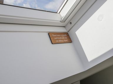 A skylight window with a small wooden sign reading turn into a giraffe and look left for an abbey view at Foxton Penthouse in Whitby