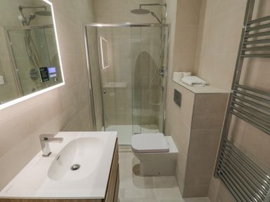A bathroom with a sink, toilet, glass shower enclosure, and towel rack at Foxton Penthouse Whitby