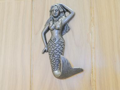 A metal mermaid-shaped wall hook attached to a wooden surface at Foxton Penthouse in Whitby