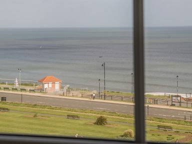 A view of the sea with a small building and road in the foreground taken from a window at Foxton Penthouse in Whitby