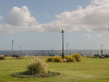 A grassy park area with benches street lamps and a view of the sea at Foxton Penthouse in Whitby