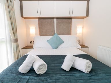 A bedroom with a double bed blue throw white rolled towels and a blue cushion at Number 10 in Warton