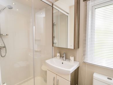 A bathroom with a shower enclosure sink with cabinet mirror and window blinds at Number 10 in Warton