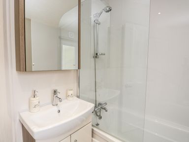 A bathroom with a sink, a mirror cabinet, and a bathtub with a showerhead at Number 10 in Warton