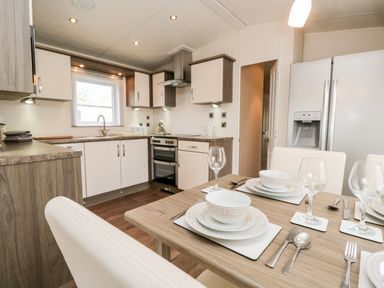 A kitchen with a dining table set with plates bowls and glasses at Number 10 in Warton