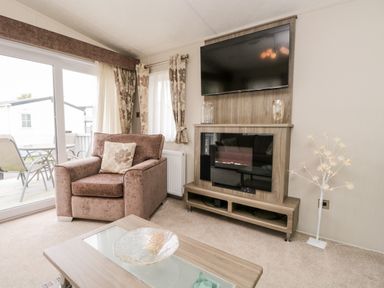A living room with an armchair and a television above an electric fireplace at Number 10 in Warton