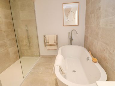 A bathroom with a freestanding bathtub and glass shower enclosure at Porth Beach in Porth near St Columb Minor