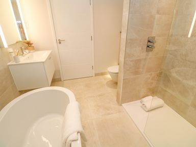 A bathroom with a bathtub a sink a toilet and a walk in shower at Porth Beach in Porth near St Columb Minor