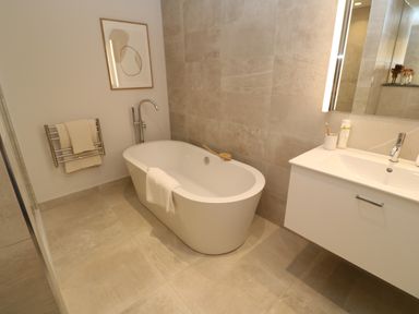A bathroom with a freestanding bathtub sink cabinet and towel rack at Porth Beach in Porth near St Columb Minor