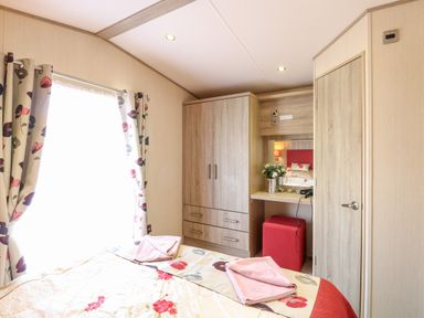 A bedroom with a bed closet vanity table window with curtains and towels on the bed at Freddys Lodge Foxburrow Hang in Fritton