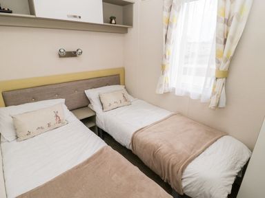 A bedroom with two single beds separated by a small nightstand at Moonlight Lodge in Bockenfield Country Holiday Park near West Thirston