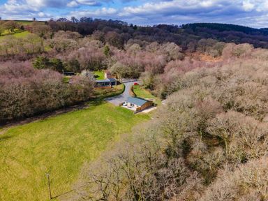 A rural landscape with several houses surrounded by trees and open grassy fields at Quantock Barn in Stockland near Honiton