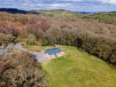 A single house with a blue roof surrounded by bare trees and grassy fields at Quantock Barn in Stockland near Honiton