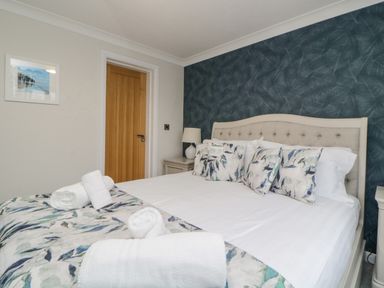 A bedroom with a large bed with patterned pillows and rolled towels at Meadow Lodge in Lifton