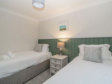 A bedroom with two single beds a nightstand and a lamp at Meadow Lodge in Lifton