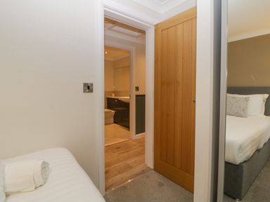 A bedroom with a bed and a towel on it next to a wooden door leading to a bathroom at Meadow Lodge in Lifton