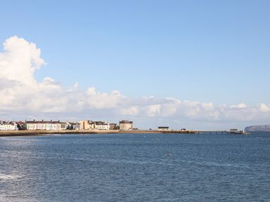 A coastal town with buildings along the shore and a pier extending into the water at Cobblers Cottage in Beaumaris