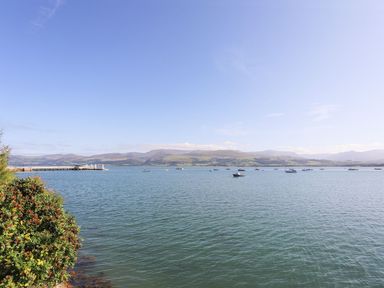 A body of water with boats and a pier with hills in the background at Cobblers Cottage in Beaumaris