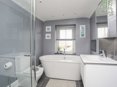 A bathroom with a bathtub toilet sink mirror and shower enclosure at Cobblers Cottage in Beaumaris