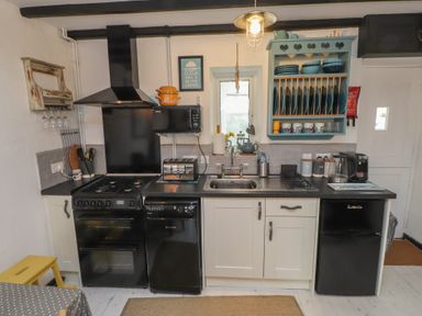 A kitchen with appliances and dishes in cabinets at Menuchah in Criccieth