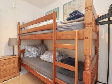 A bedroom with a bunk bed and bedside lamp at Menuchah in Criccieth