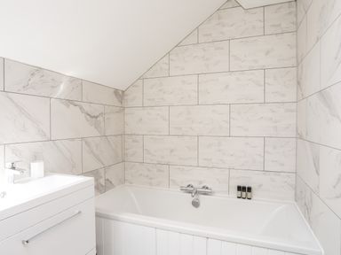 A bathroom with a bathtub and a sink with a faucet at The Stables in Penmon near Beaumaris