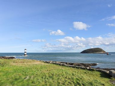 A coastal scene with a lighthouse sea and an island at The Stables in Penmon near Beaumaris