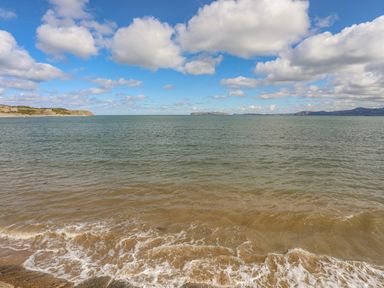 A seascape with cloudy blue sky sandy shore and distant land at The Stables in Penmon near Beaumaris