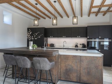 A modern kitchen with an island counter and bar stools at The Stables in Penmon near Beaumaris