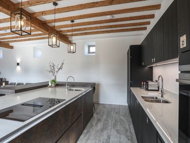 A kitchen with two sinks and wooden ceiling beams at The Stables in Penmon near Beaumaris