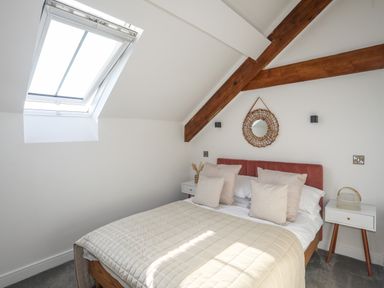 A bedroom with a bed with pillows and blankets under a skylight window at The Stables in Penmon near Beaumaris