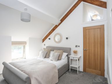 A bedroom with a double bed pillows bedside tables and a wooden door at The Stables in Penmon near Beaumaris