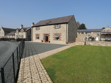 Stone houses with a gravel driveway lawn and a paved path at The Stables in Penmon near Beaumaris