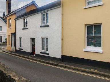 A street view of adjoining houses with white and yellow exteriors and windows at Hope Cottage in Buckfastleigh