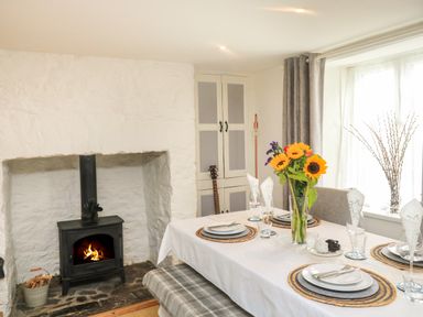 A dining room with a fireplace a table set for dinner and sunflowers in a vase at Hope Cottage in Buckfastleigh