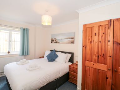 A bedroom with a double bed bedside tables and wooden wardrobe at Garland Nottington near Weymouth