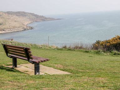 A bench on a grassy hill overlooking the sea and a rocky coastline at Garland in Nottington near Weymouth