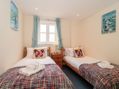 A bedroom with two single beds with butterfly pillows and folded towels at Mellstock in Nottington near Weymouth