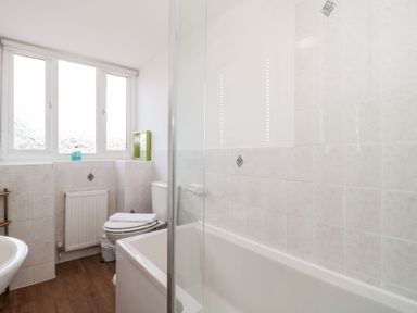 A bathroom with a bathtub shower screen toilet sink and windows at Mellstock in Nottington near Weymouth