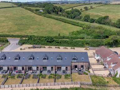 A row of houses with fenced gardens surrounded by green fields at Mellstock in Nottington near Weymouth