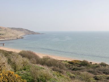A coastline with a sandy beach shrubs and hills at Mellstock in Nottington near Weymouth