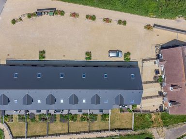 An aerial view of a row of houses with backyards and a parking area with a car at Mellstock in Nottington near Weymouth