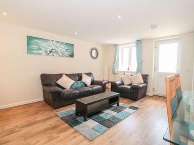 A living room with leather sofas a coffee table and a patterned rug at Emminster Nottington near Weymouth