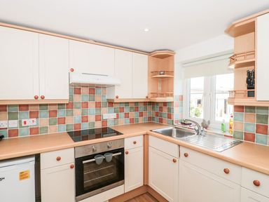 A kitchen with a stove oven sink and multicolored tiled backsplash at Emminster in Nottington near Weymouth