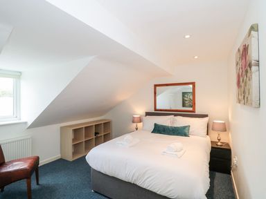 A bedroom with a double bed lamps on bedside tables a chair and a window at Emminster in Nottington near Weymouth