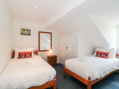 A bedroom with two single beds a bedside table with a lamp a wall mirror and a wardrobe at Emminster in Nottington near Weymouth